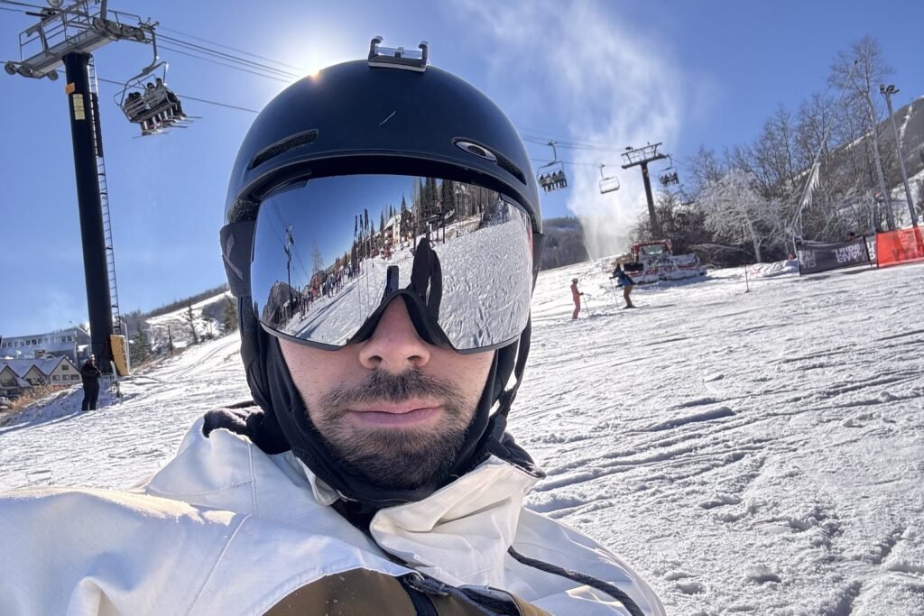 Tomás con casco y antiparras en una pista con un telesilla detrás
